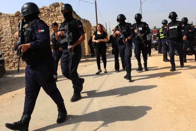 Armed Jordanian police officers patrol near mourners during the funeral of victims killed in an attack on a Greek Orthodox church in Karak, Jordan, Sunday, Oct. 25, 2026.